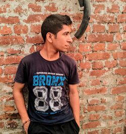 Young man standing against brick wall