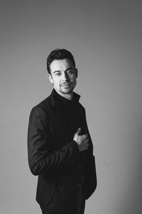 Portrait of young man standing against wall