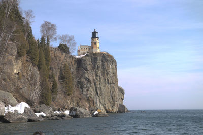 Split-rock observatory and lighthouse by sea against sky