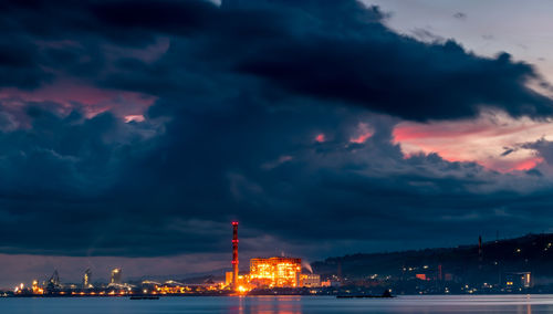 Illuminated city against sky at sunset