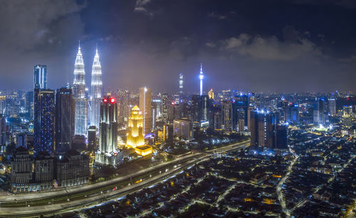 Illuminated modern buildings in city against sky at night