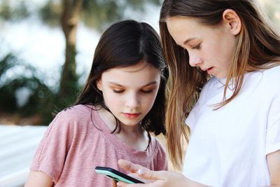 Girls looking at phone while standing outdoors