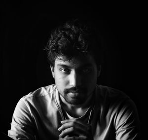 Portrait of young man against black background