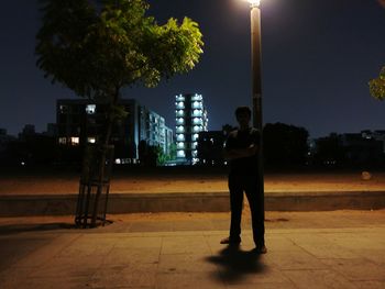 Man standing on illuminated street at night