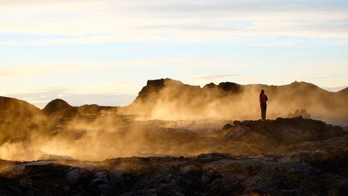 Man on rock formations against sky