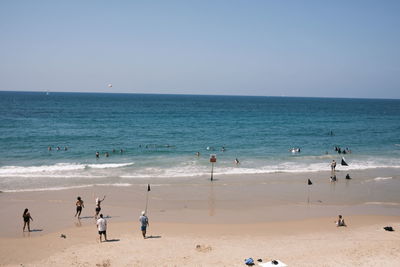 Group of people on beach against clear sky