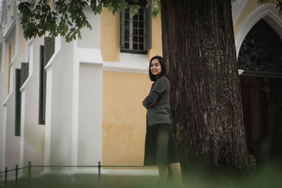 Full length of young woman standing against building