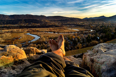 Low section of man standing on rock against sky