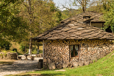 Stone wall of house and trees on field