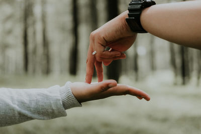 Cropped hands of people against trees