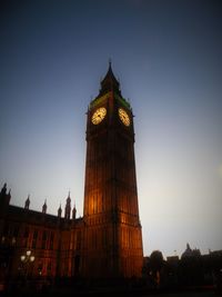 Low angle view of clock tower at night