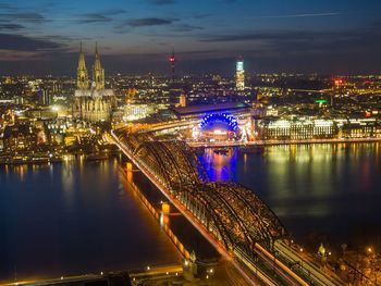 Illuminated bridge over river in city at night