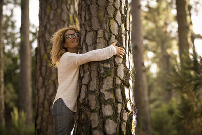 Side view of woman hugging tree outdoors