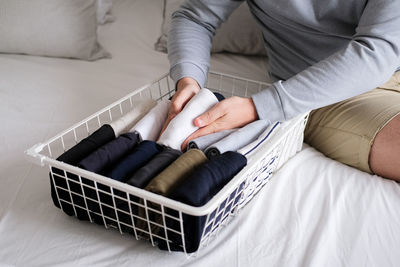 Low section of woman sitting on bed at home