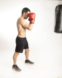 Full length of shirtless man standing against white background