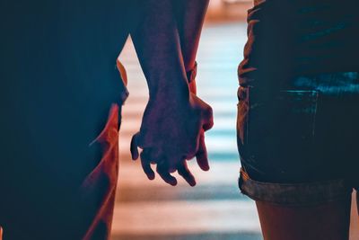 Midsection of couple holding hands standing outdoors