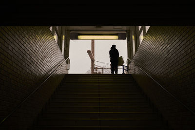 Low angle view of silhouette woman standing on staircase