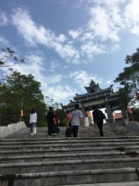 People walking on staircase against sky