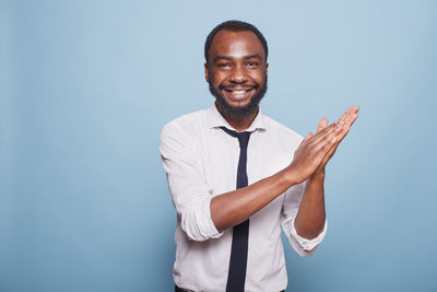 Portrait of young man with arms crossed standing against white background