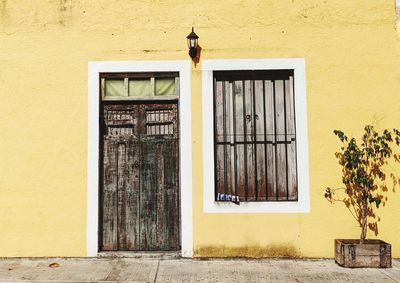 A closed window and door on a yellow wall