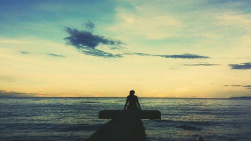 Silhouette woman on beach against sky during sunset