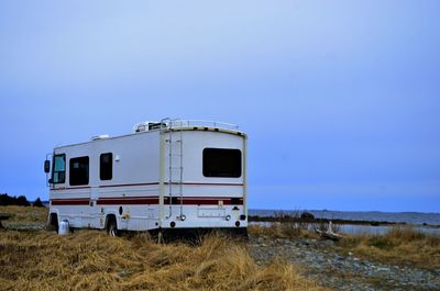 View of parked caravan against landscape and clear blue sky