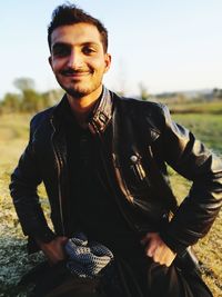 Portrait of smiling young man sitting on field