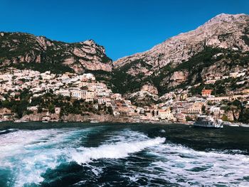 Scenic view of sea by buildings against clear blue sky