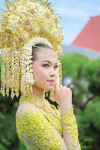 Portrait of young woman standing against trees