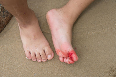 Low section of baby feet on sand