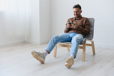 Young man sitting on hardwood floor at home