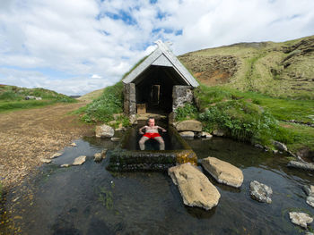 Man relaxing in a small geothermal hot spring pool in hrunalaug, iceland