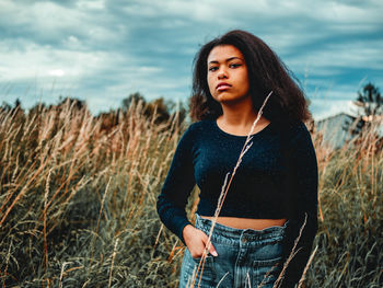 Portrait of woman standing on field against sky