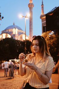 Young woman eating food in city