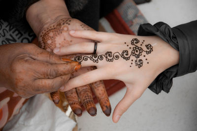 Cropped image of woman making henna tattoo on female friend hand