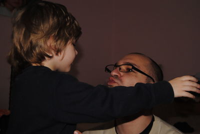 Son embracing father against wall at home