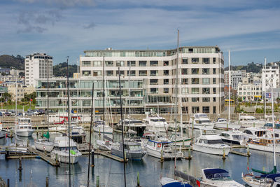 Boats moored at harbor against buildings in city