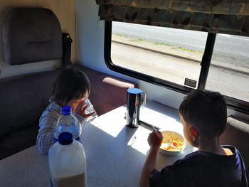 Siblings having food and drink in train