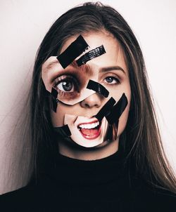 Portrait of young woman holding eyeglasses against white background