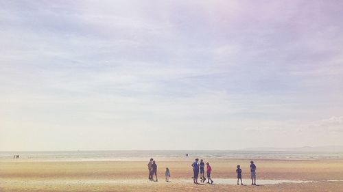 People walking on beach against sky