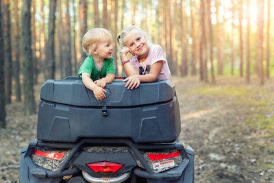 Girl with brother in quadbike at forest