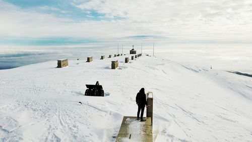 Rear view of person standing on snow covered field against sky