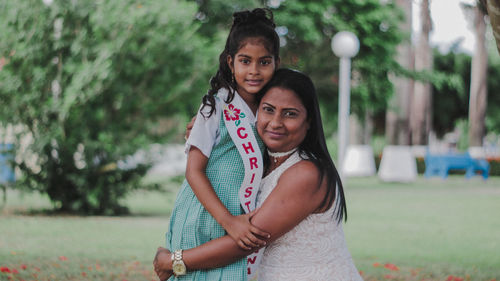 Portrait of mother hugging daughter in park