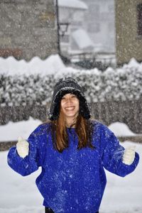 Portrait of smiling young woman standing on snow
