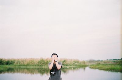 Young woman standing on field against sky