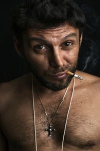 Portrait of man with cigarette against black background