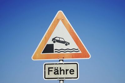 Road sign against clear blue sky