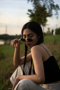 Young woman wearing sunglasses sitting on field