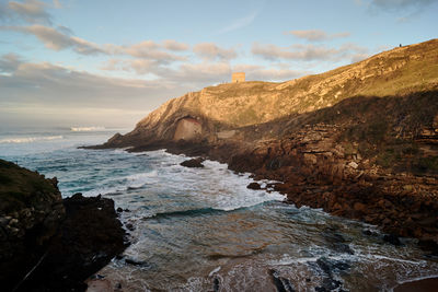 Rock formation on beach against sky