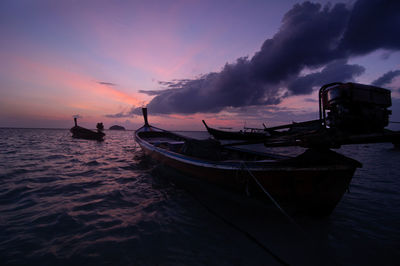 Silhouette boats moored on sea against sky during sunset